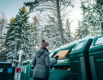 Kvinna lämnar en kartong på en återvinningsstation